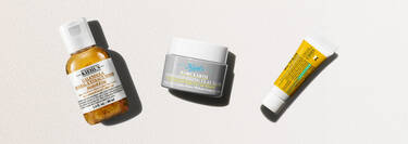Tre Kiehl's hudplejeprodukter på en lys baggrund: Calendula-toner, Rare Earth-lermaske og en lille gul tube.