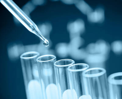 A pipette releasing a drop of liquid into a row of test tubes, with a DNA double helix structure faintly visible in the background.