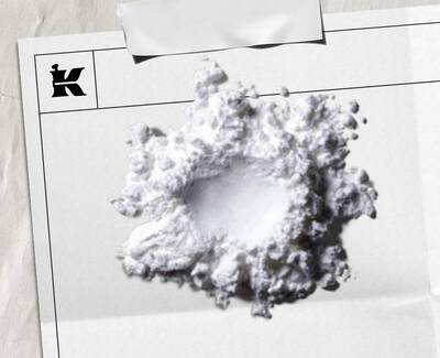 A dropper is poised above several petri dishes filled with a light blue liquid, illustrating a laboratory setting.