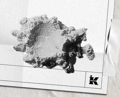 Et struktureret, uregelmaessigt formet hvidt mineral- eller materialefragment, der hviler på en lys baggrund, med et lille logo nederst til højre.