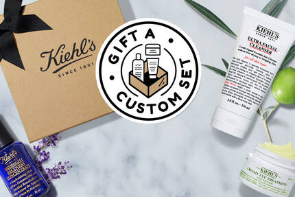 Gaveaeske med Kiehl's hudplejeprodukter, herunder ansigtscreme og serum, praesenteret med et brunt papirpose og logo.