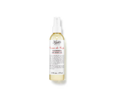 A bottle of Kiehl's Creme de Corps Nourishing Dry Body Oil, featuring a spray nozzle and a clean, minimalist label design.