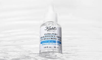 A clear bottle of Kiehl's Ultra Pure High-Potency Serum with 15% hyaluronic acid, featuring a simple white label and blue accents, set against a soft, blurred background.
