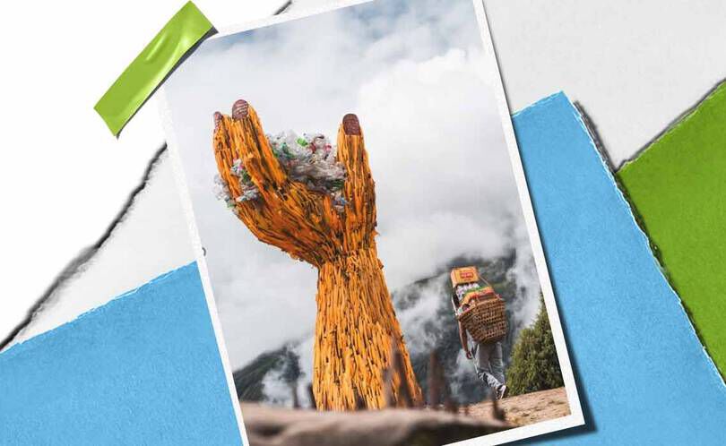 En tårnhøj håndskulptur af trae holder en bunke affald, der symboliserer miljøbevidsthed, med en person, der baerer varer i naerheden.