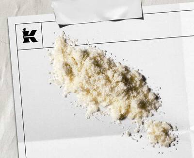 En bunke hvidt pulver på et blankt stykke papir med et logo i hjørnet, hvilket antyder en kunstnerisk eller stilistisk praesentation.