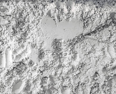 A close-up of a textured surface consisting of fine, powdery white material, with imprints and variations in thickness.