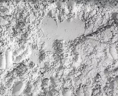 A close-up of a textured surface consisting of fine, powdery white material, with imprints and variations in thickness.