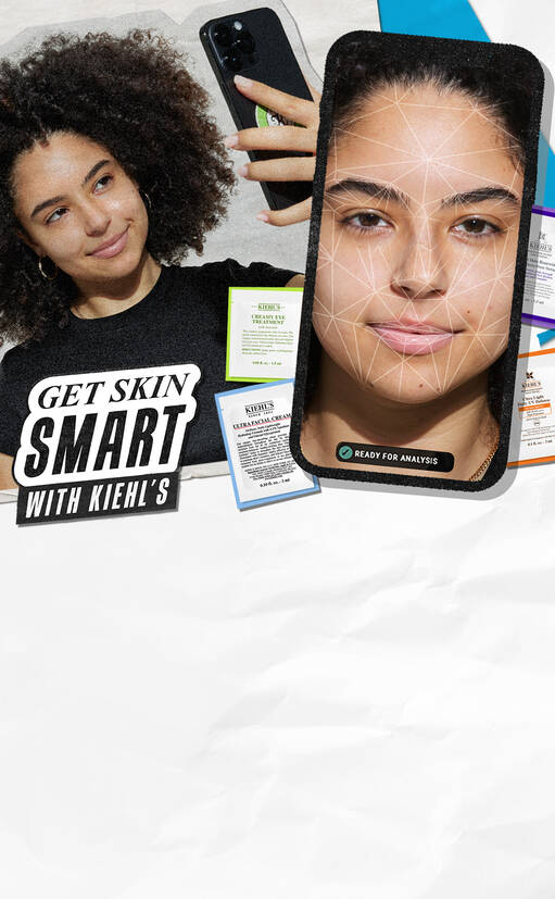 En person med krøllet hår smiler, mens de holder en smartphone. Skaermen viser en ansigtsanalyse. Omkring er forskellige farverige hudplejeprodukter fra Kiehl's. Teksten "GET SKIN SMART WITH KIEHL'S" fremhaeves.