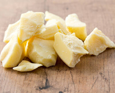 Chunks of yellow cocoa butter scattered on a wooden surface.