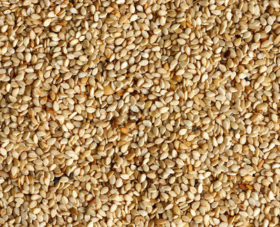 A close-up image of a large pile of beige sesame seeds, highlighting their tiny, oval shapes and varied textures.