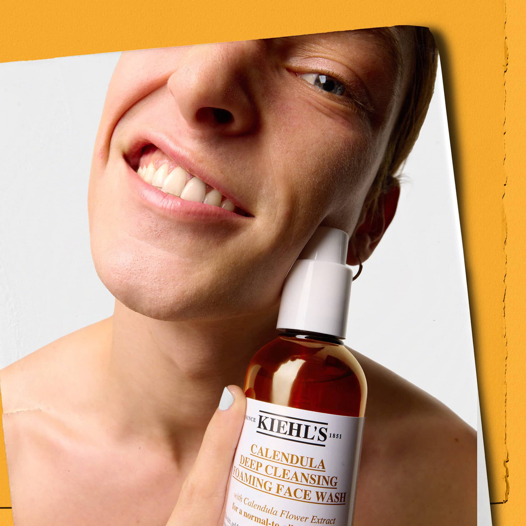 Model holder en flaske med Kiehl's Calendula Deep Cleaning Foaming Face Wash