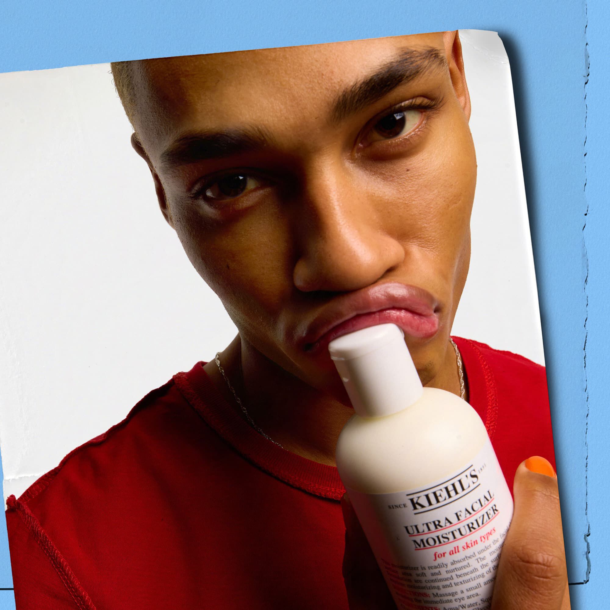 Model, der presser en flaske Kiehl's Ultra Facial Moisturizer mod sine laeber
