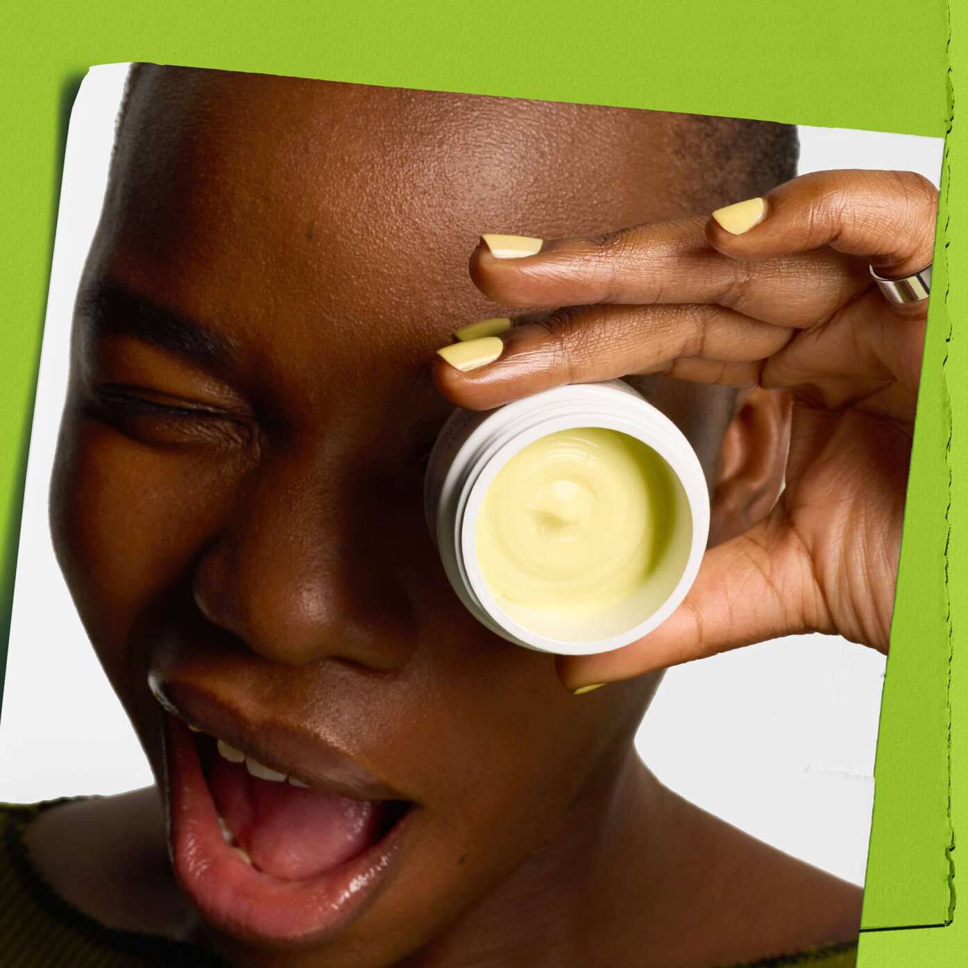 Blinkende model med en krukke Kiehl's Creamy Eye Treatment with Avocado, der daekker det ene øje