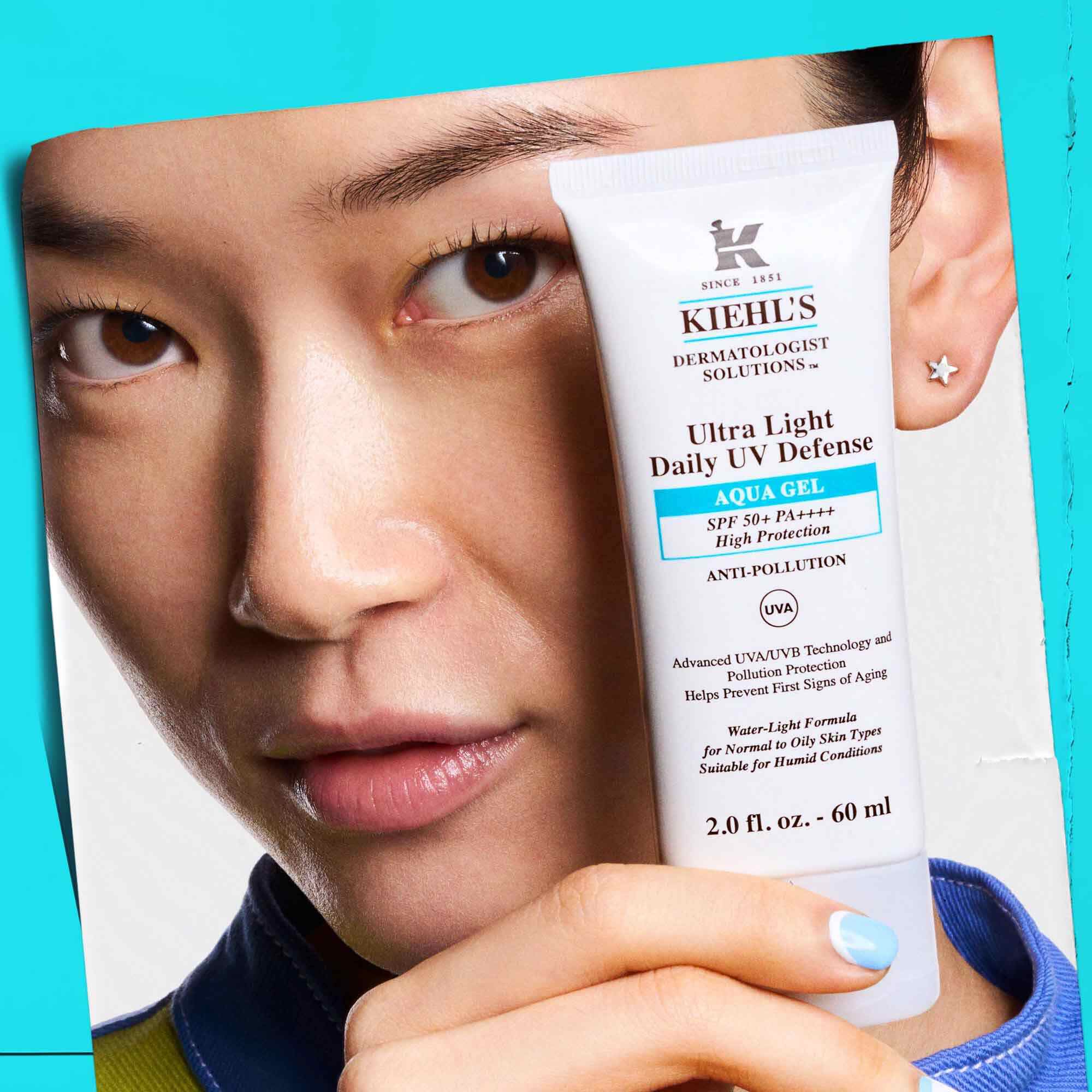 En model, der holder en tube Ultra Light Daily UV Defense Aqua Gel, hvilket viser dens baerbarhed og brugervenlighed.