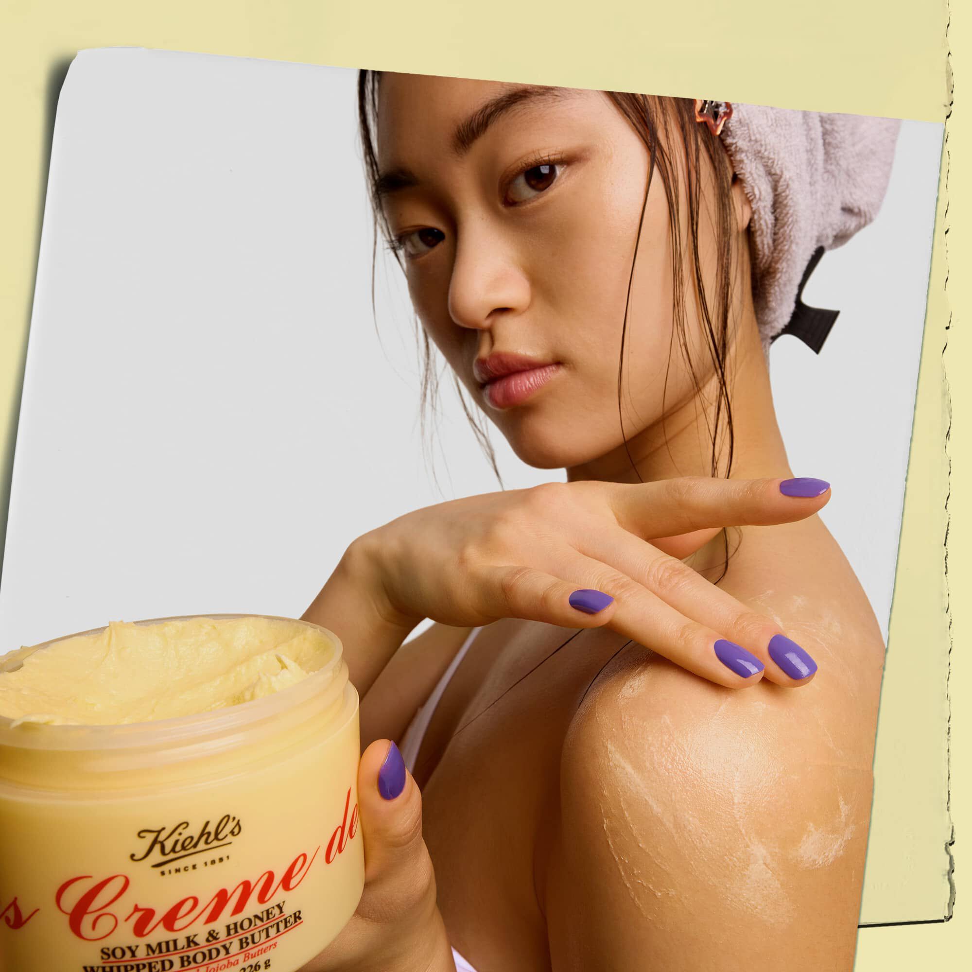 Model holder en krukke og påfører Kiehl's Creme de Corps Whipped Butter bodybutter