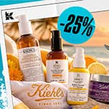 Kiehl's hudplejeprodukter, inklusive ansigtsvask, serum og creme, sat op mod en smuk solnedgang på stranden.