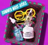 A green and pink woven basket containing Kiehl's skincare products including Ultra Facial Cream and serums, with yellow sunglasses and a 'Summer Must-Haves' sticker.
